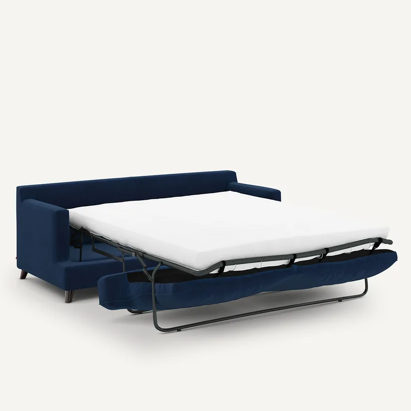Canapé Alwine bleu marine déplié en lit, matelas blanc posé sur un sommier à lattes métalliques.