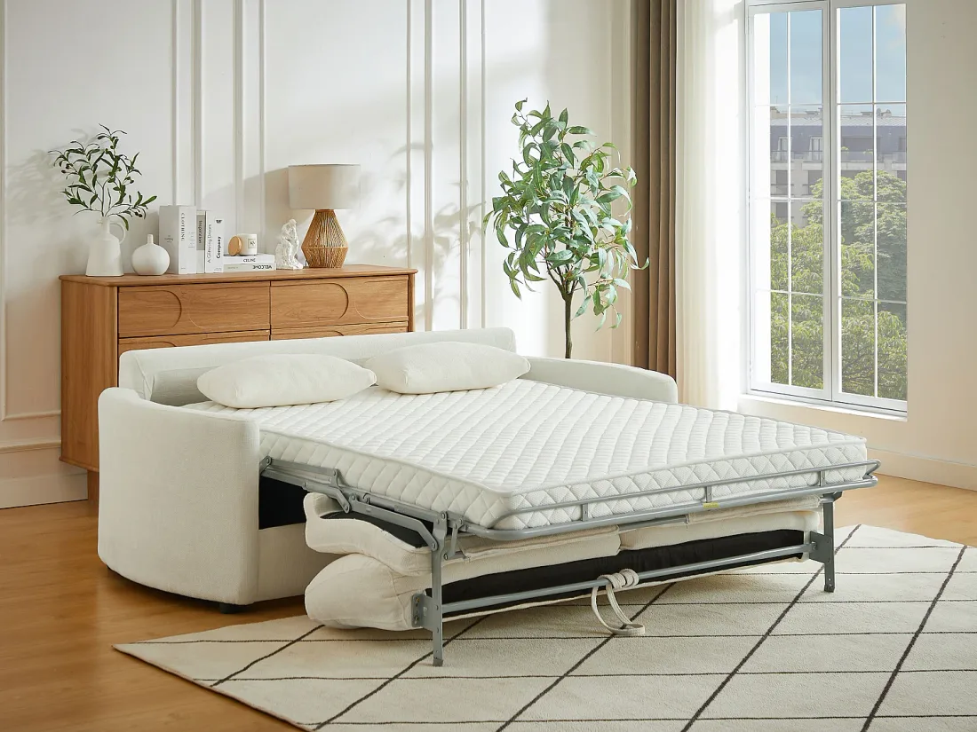 Canapé Bagomi ouvert en lit, matelas blanc matelassé déplié sur une armature métallique, dans un salon lumineux.