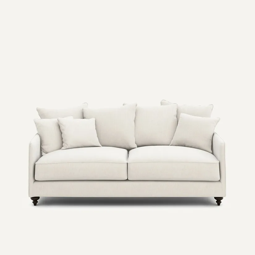 Canapé Lazare trois places en tissu beige clair uni, coussins assortis, pieds sombres, fond blanc.