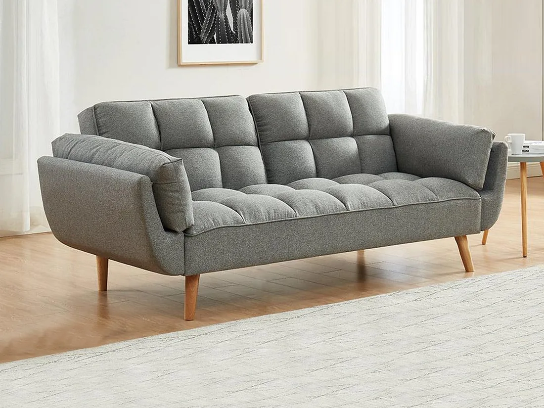 Canapé Loeline en tissu gris clair dans un salon, avec des pieds en bois et un tapis beige.