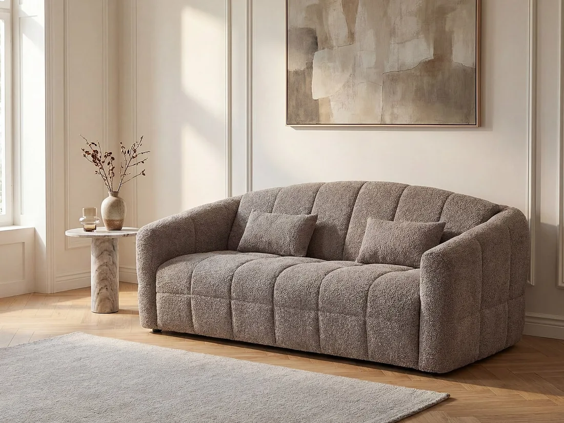 Canapé Retuna taupe en bouclette dans un salon clair, avec une table d'appoint en marbre et un tableau.